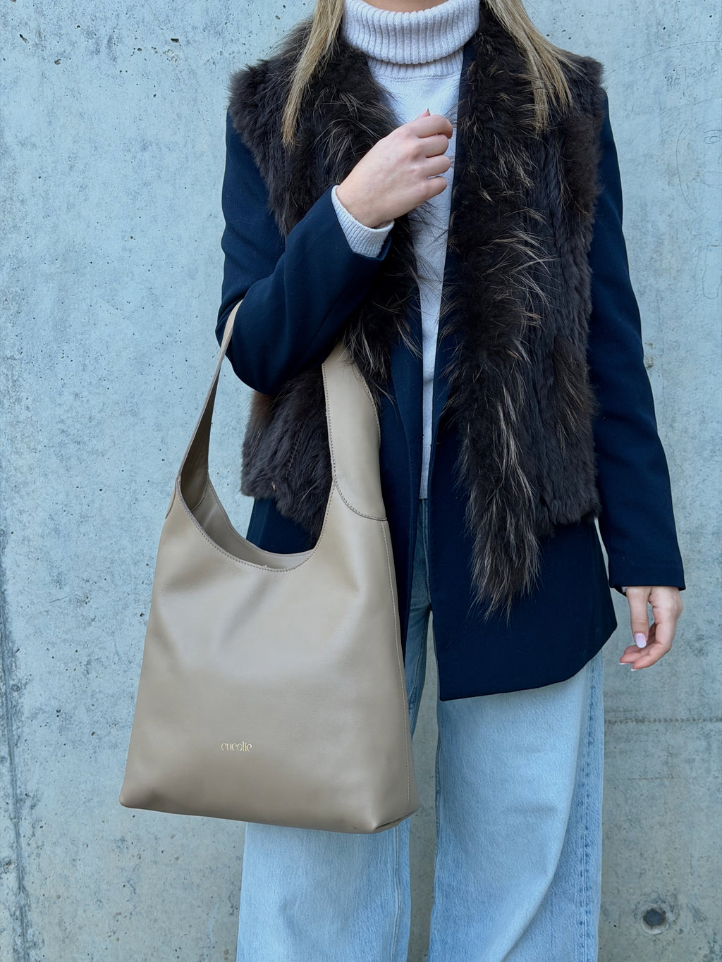 Bolso Cucolie de piel color taupe llevado al hombro, con chaleco de pelo